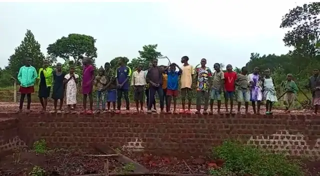 Children standing along the brick foundation walls of a house under construction