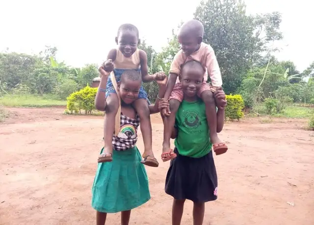 Two girls laughing as they carry two younger children on their shoulders